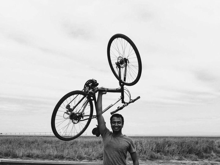 Holding the bike overhead with one arm at the end of the ride, black and white